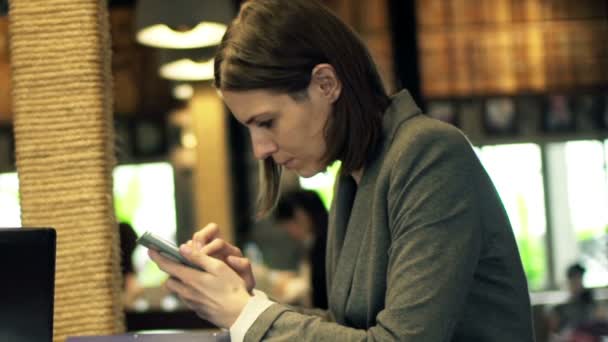 Zakenvrouw gebruikend smartphone zittend in café — Stockvideo
