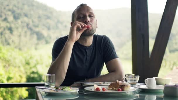 Happy man eating breakfast on terrace — Stock Video