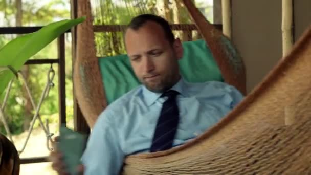Znudzony biznesmen leżącego na hamaku na tarasie — Wideo stockowe