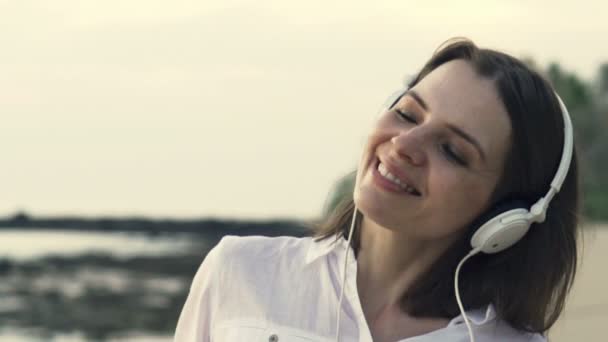 Vrouw luisteren naar muziek en dansen op het strand — Stockvideo