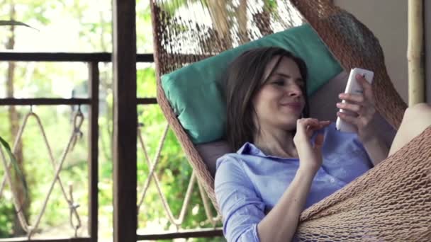 Woman with smartphone lying on hammock — Stock Video