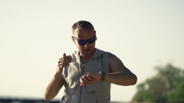 Чоловічий бігун перевіряє пульс на смарт-годиннику на пляжі — стокове відео