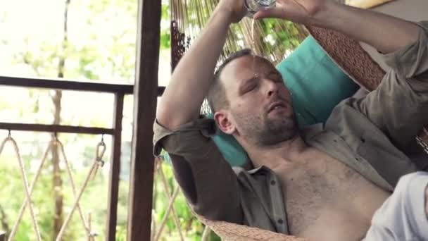 Человек охлаждается водой на гамаке — стоковое видео