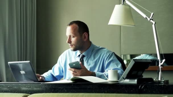 Homme d'affaires comparant les données sur smartphone, ordinateur portable et documents — Video