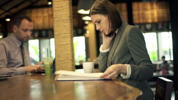 Επιχειρηματίες με έγγραφα και smartphone που κάθεται σε καφετέρια — Αρχείο Βίντεο
