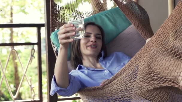 Vrouw drinken en het verhogen van de toast op hangmat — Stockvideo