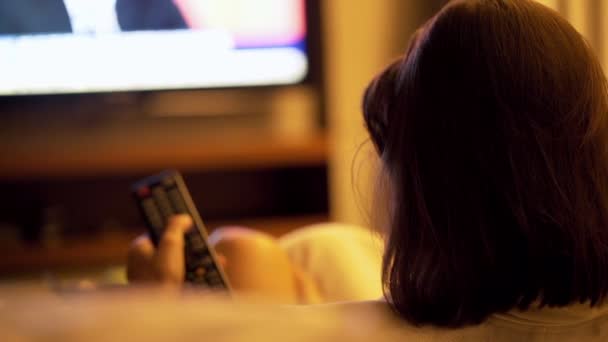 Femme regardant la télévision sur le canapé la nuit — Video