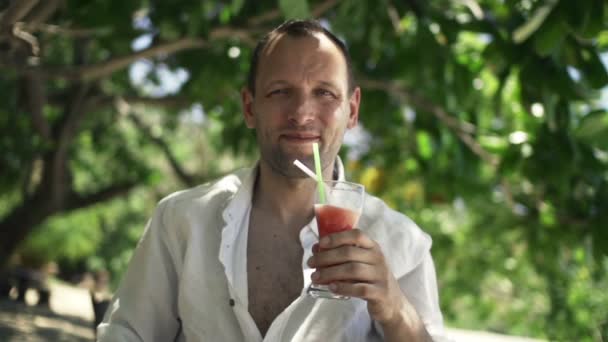 Man raising toast and drinking cocktail in park — Stock Video