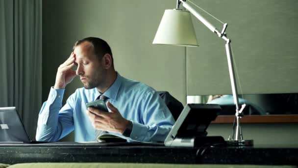 Бизнесмен, работающий со смартфоном, ноутбуком и документами — стоковое видео