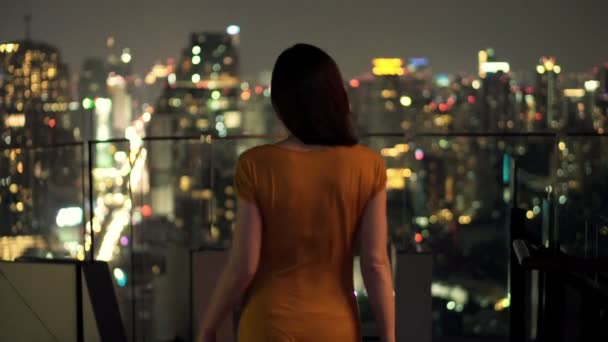 Молода жінка дивиться на міський пейзаж вночі — стокове відео