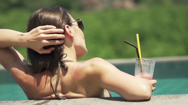 Женщина в бассейне расслабляется с коктейлем — стоковое видео