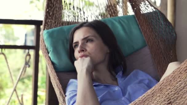 Συλλογισμένος γυναίκα ξαπλωμένη στην αιώρα στην βεράντα — Αρχείο Βίντεο