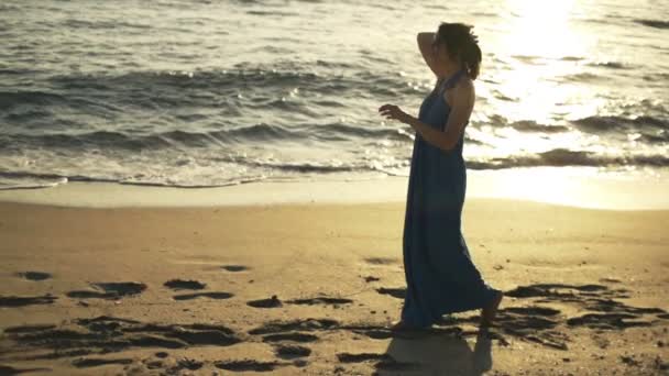 Mujer caminando en la playa al atardecer — Vídeos de Stock