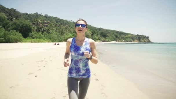 Молода жінка біжить на екзотичному пляжі — стокове відео
