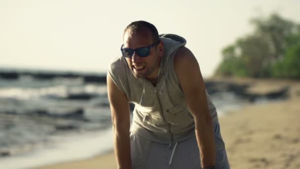 Mannelijke jogger nemen pauze op strand — Stockvideo