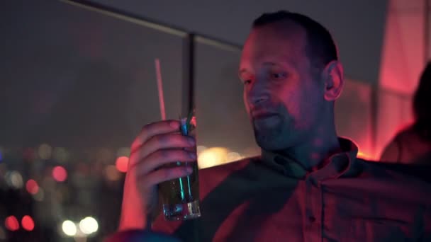Мужчина пьет коктейль на террасе в кафе — стоковое видео