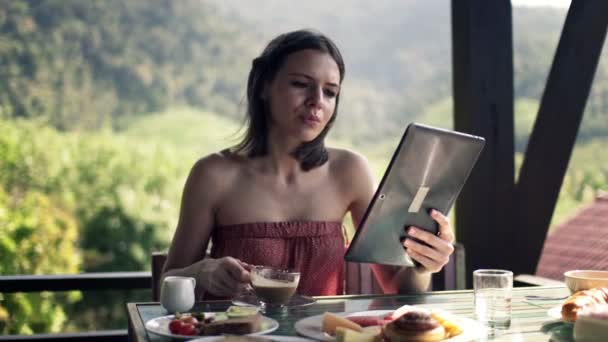 Woman using tablet computer and drinking coffee — Stock Video