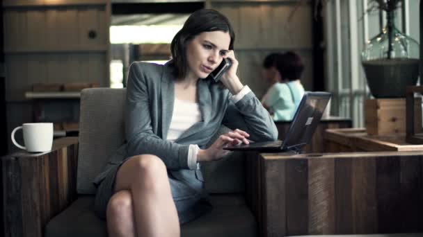 Mujer de negocios con teléfono celular y portátil que trabaja en la cafetería — Vídeos de Stock