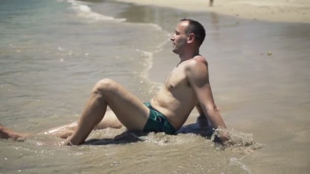 Homem bonito relaxante e banhos de sol na praia — Vídeo de Stock