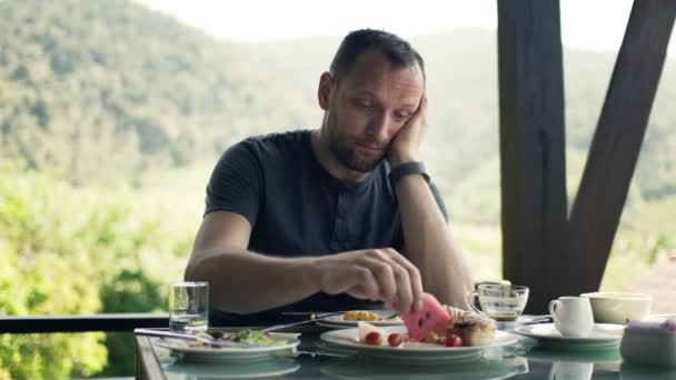 Man äter frukost av bord på terrassen — Stockvideo