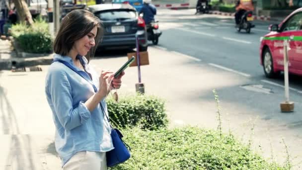 Жінка зі смартфоном, що стоїть в місті — стокове відео