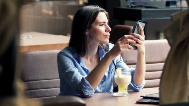 Mujer escuchar música en el teléfono celular y beber cóctel — Vídeo de stock