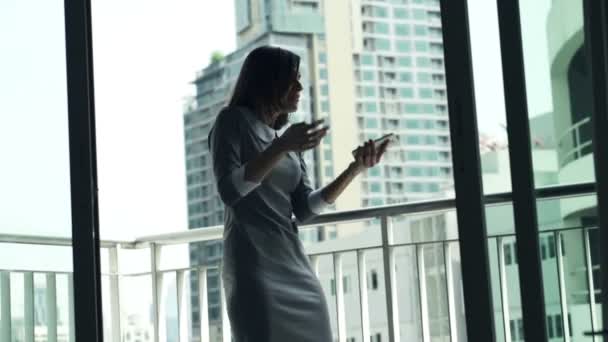 Злая деловая женщина разговаривает по мобильному телефону на террасе — стоковое видео