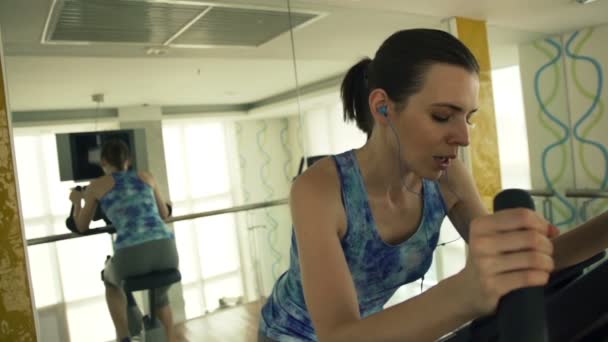 Jeune femme à vélo stationnaire dans la salle de gym — Video