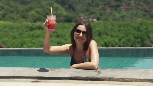 Mujer levantando tostadas y bebiendo cóctel en la piscina — Vídeos de Stock