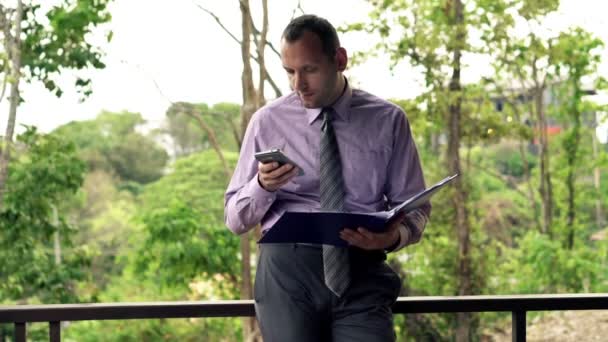 Businessman comparing data on smartphone and documents — Stock Video