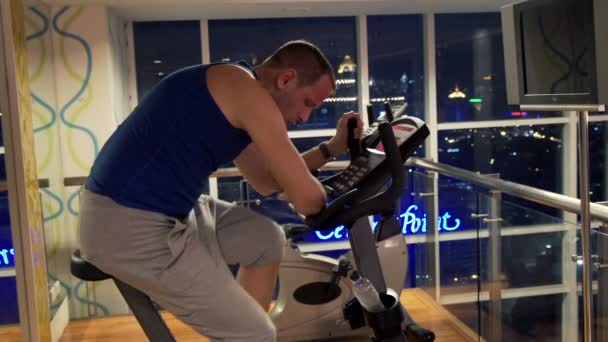 Man taking break while riding stationary bike in gym — Stock Video