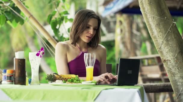 Mulher com laptop comendo abacaxi no café — Vídeo de Stock