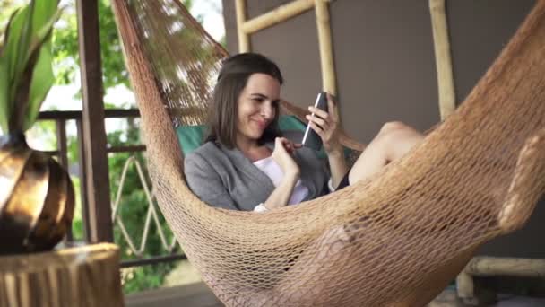 Affärskvinna med smartphone ligger på hammock — Stockvideo