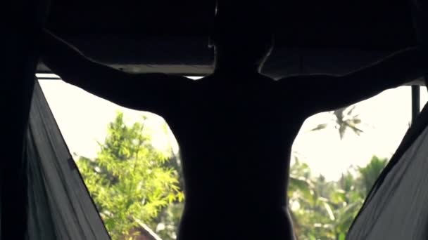 Mann enthüllt Vorhänge und geht auf Terrasse — Stockvideo