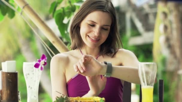 Vrouw met smartwatch zitten in exotische Cafe — Stockvideo
