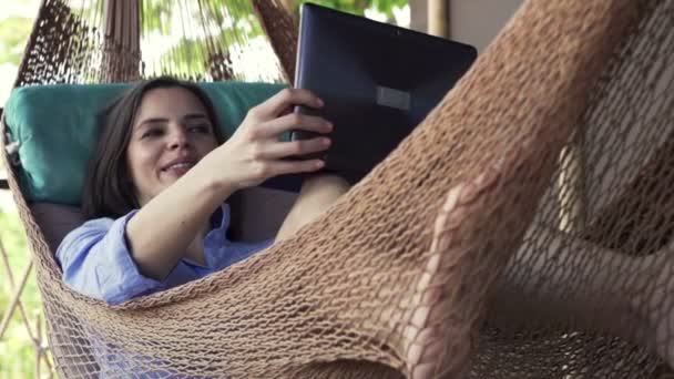 Kvinna som chattar på laptop ligger på hammock — Stockvideo