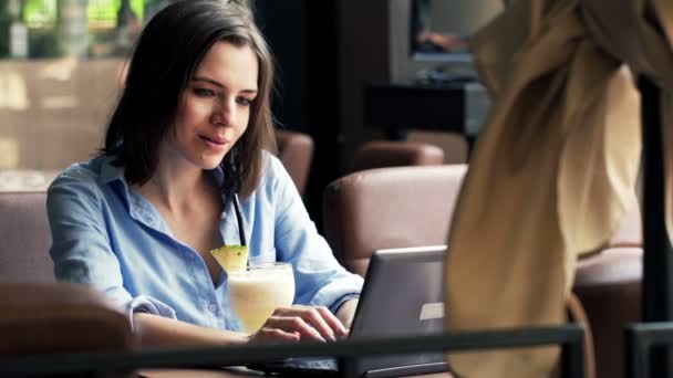 Γυναίκα με φορητό υπολογιστή και πίνοντας κοκτέιλ στο καφέ — Αρχείο Βίντεο