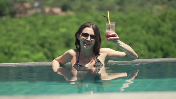 Donna che solleva brindisi e beve cocktail in piscina — Video Stock