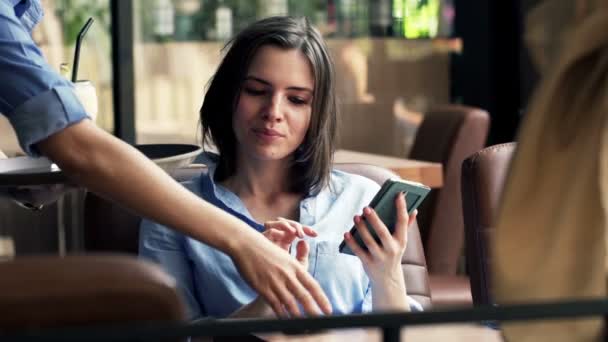 Mujer con teléfono inteligente obtiene cóctel de camarero — Vídeo de stock