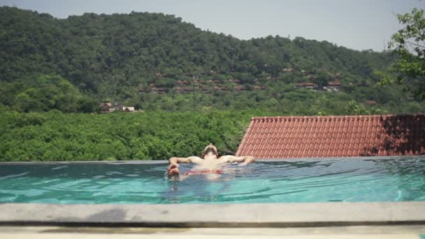 Hombre joven relajándose en la piscina — Vídeo de stock