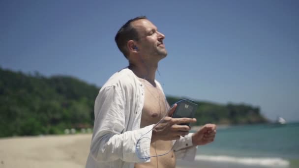 Homem ouvindo música e dançando na praia — Vídeo de Stock