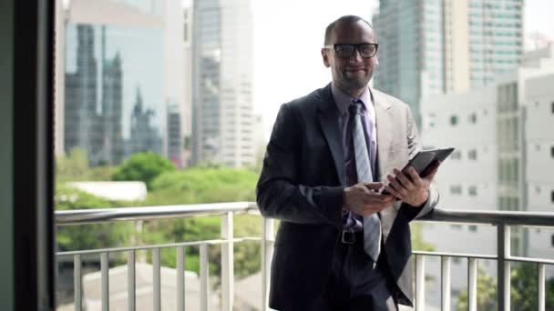 Бизнесмен с планшетным компьютером стоит на террасе — стоковое видео