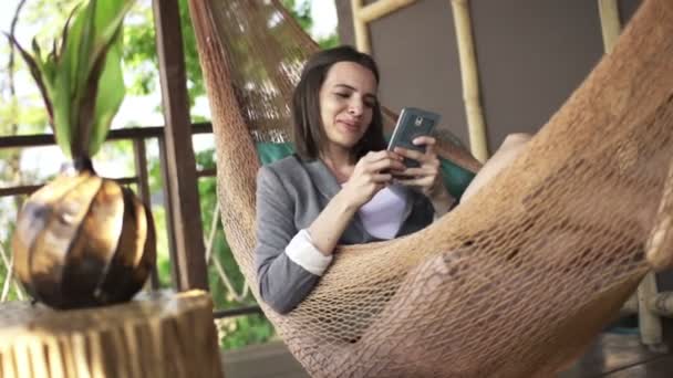 Affärskvinna med smartphone ligger på hammock — Stockvideo