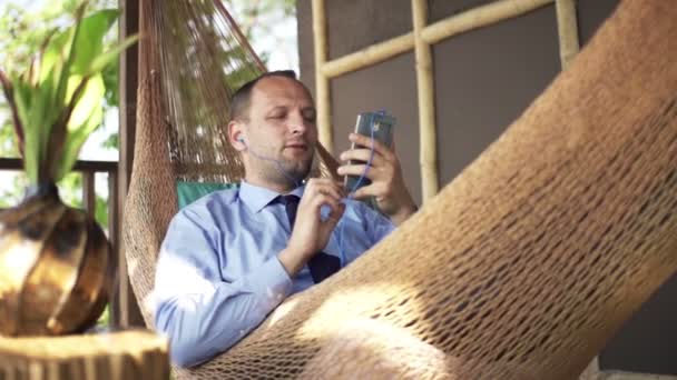 Hombre de negocios escuchando música y cantando en hamaca — Vídeos de Stock