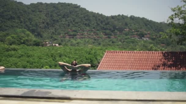 Hombre estirando los brazos y relajándose en la piscina — Vídeo de stock