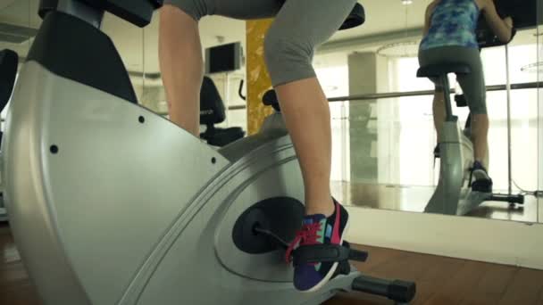 Nogi kobiety, jazda na rowerze stacjonarnym w siłowni — Wideo stockowe