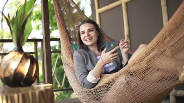 Businesswoman singing while listening to music on hammock — Stock Video