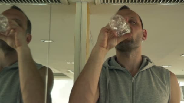 Hombre beber agua después del entrenamiento en el gimnasio — Vídeos de Stock