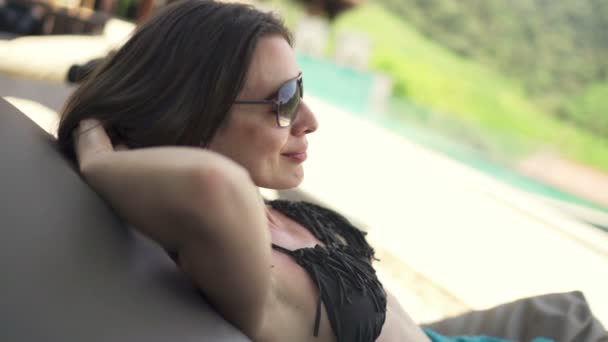 Mujer bonita relajándose en la cama de sol en la piscina — Vídeos de Stock