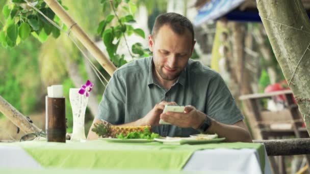 Hombre usando el teléfono inteligente y beber cóctel en la cafetería — Vídeo de stock